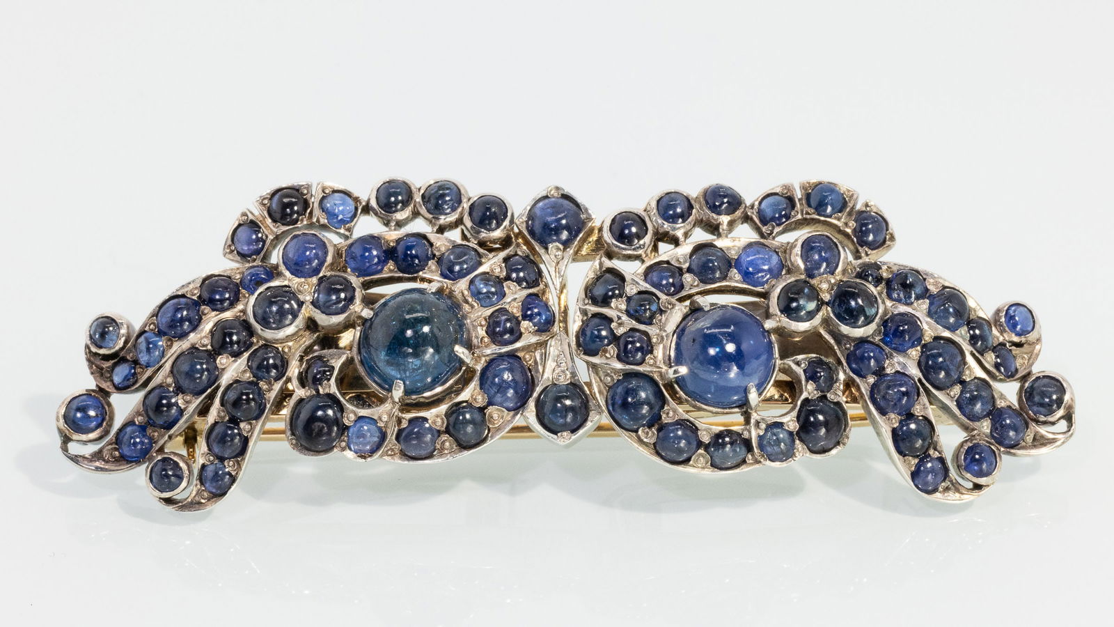 Art Deco 10K and Sapphire Pin/Dress Clips: Property from a Private Collection, Jacksonville, FLDescription: Art Deco 10K and Sapphire Pin/Dress Clips, 10K white and yellow gold mounted with various blue sapphire cabochons, with stick pin at