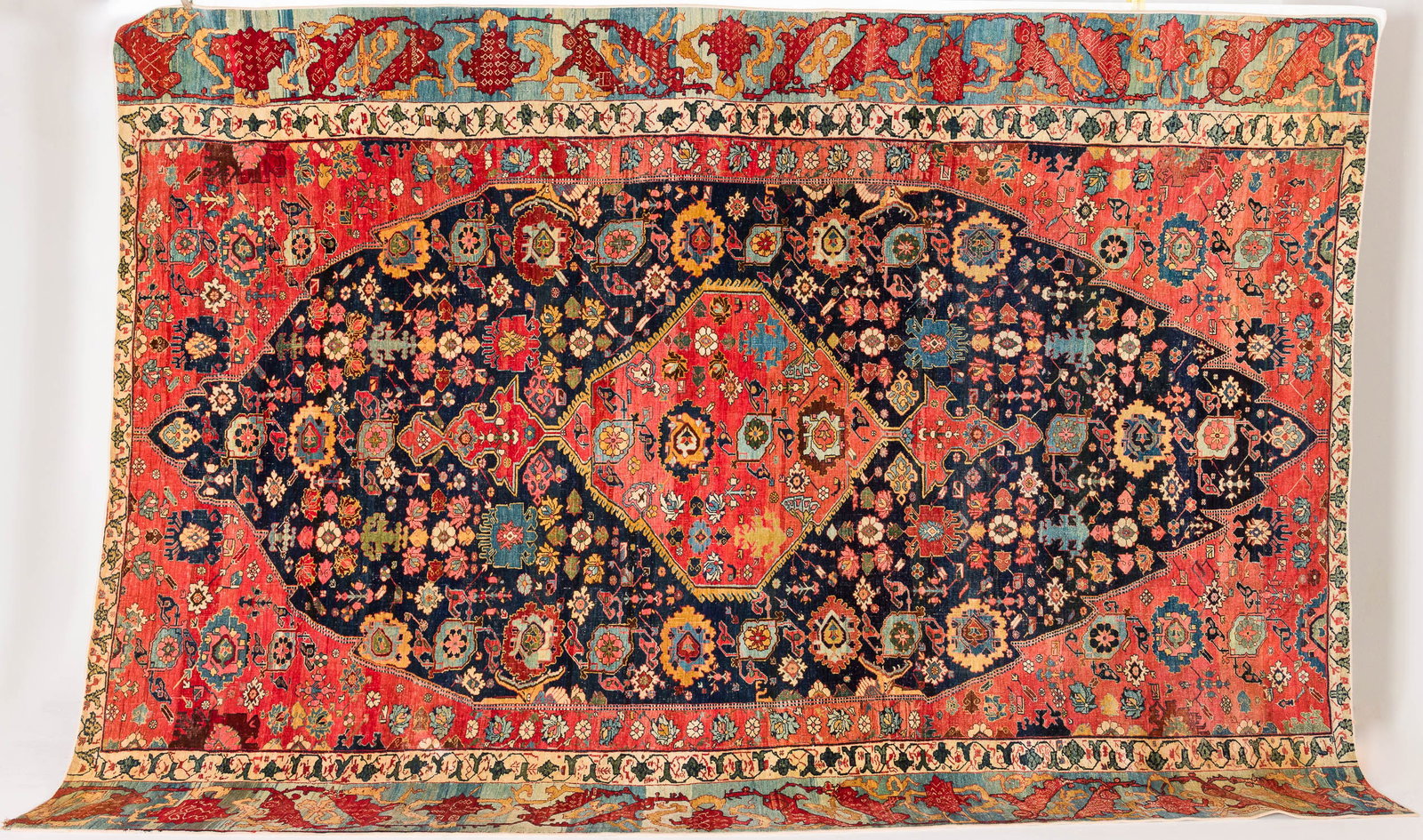 Large Antique Persian Wool Carpet: Property from a Private Collection, Bluffton, SC Description: Large Antique Persian Wool Carpet, in tones of cream, ochre, light blue, and red on a dark blue and red ground. Measurements