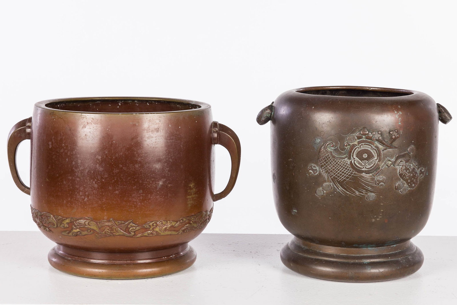 2 Japanese Bronze Planters: Description: 2 Japanese Bronze Planters, comprising one planter with decorative handles and fan decorations on front, and a bronze handled planter with phoenix and cloud motif along bottom edge (9