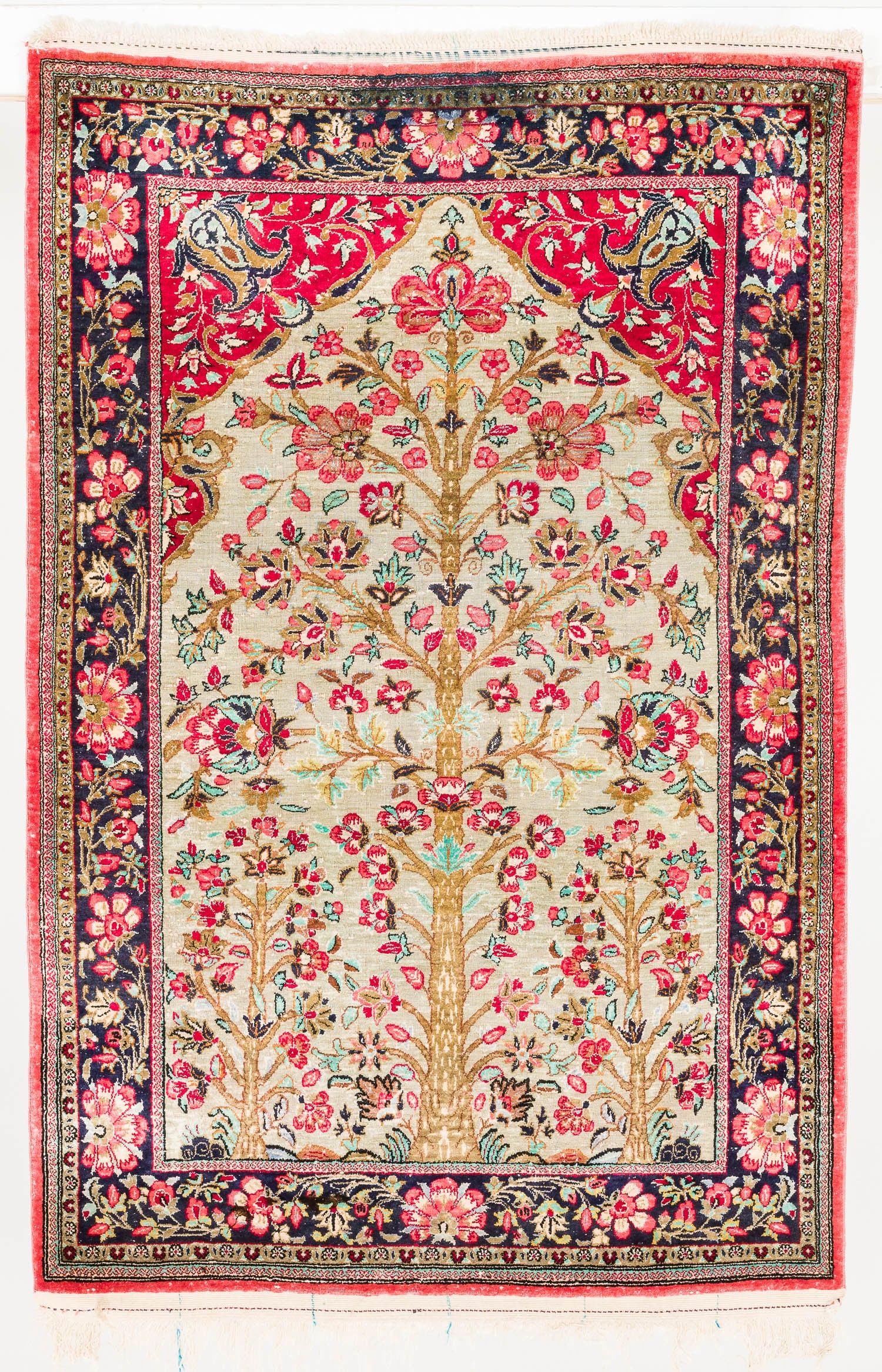 Persian Silk Prayer Rug: Description: Persian Silk Prayer Rug, in tones of red, dark blue, and cream on a salmon ground, decorated with flowers and trees. Measurements: Length: 50 in. x Width: 32,5 in.