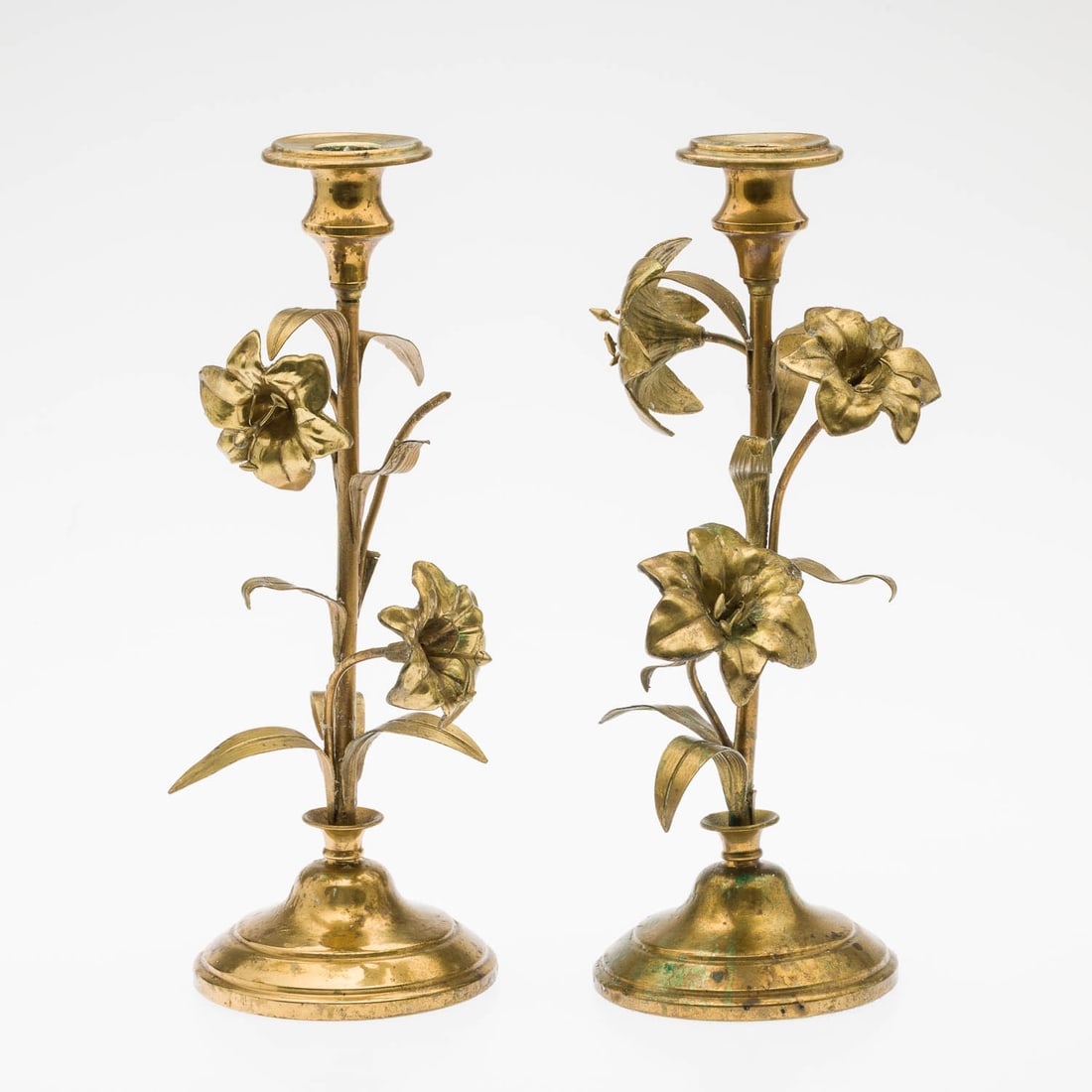 Pair of Brass Lily Candlesticks: Description: Pair of Brass Lily Candlesticks, single light candlesticks with lily flower stems. Measurements: Height: 12 in. x Width: 5 in. x Depth: 5 in.
