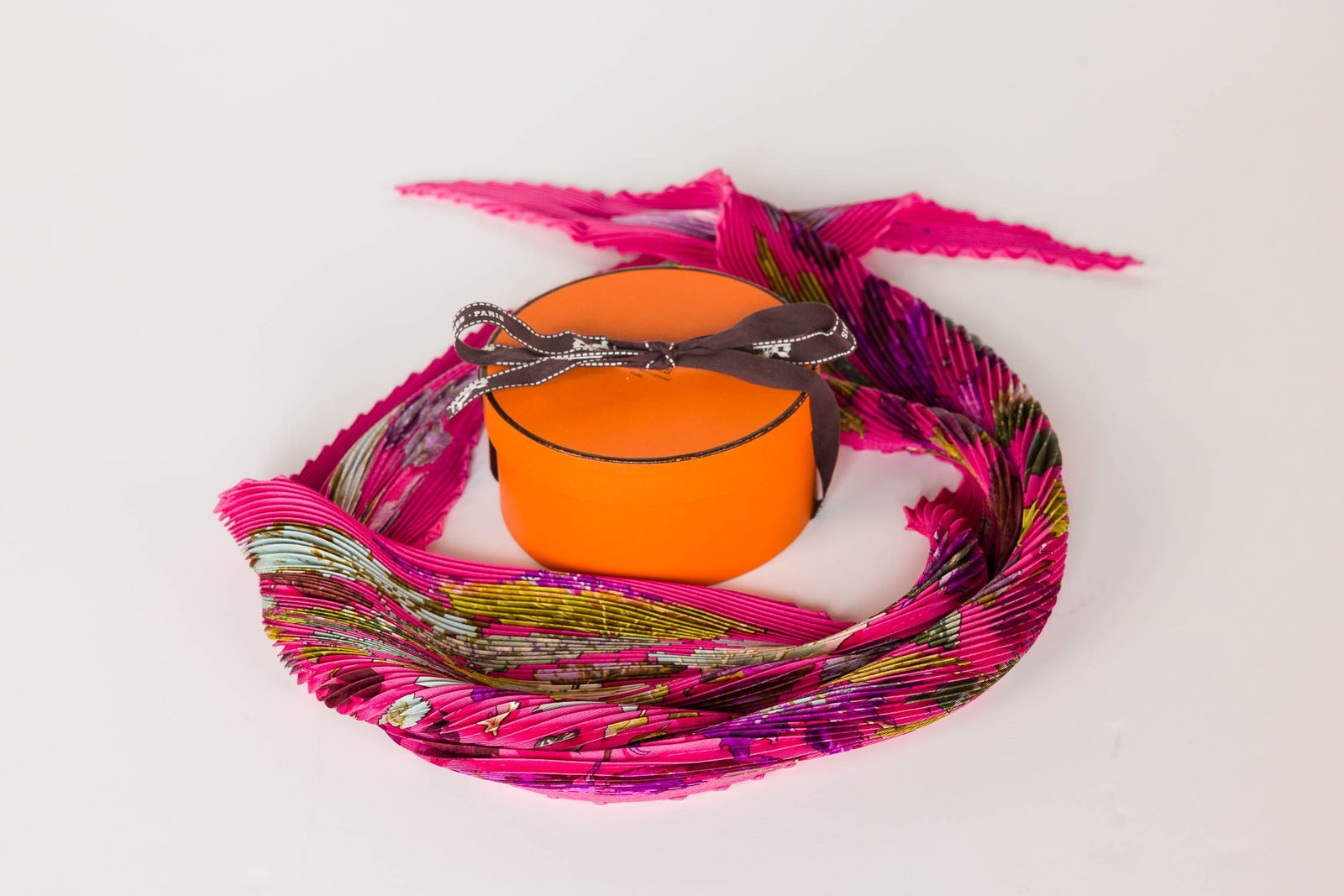Hermes Plisse Scarf and Box: Description: Hermes Plisse Scarf and Box, depicting Tourbillons (Autumn Leaves) motif on a fuchsia background, designed by Christiane Vauzelles, with box. Measurements: Height: 34 in. x Width: 34 in.