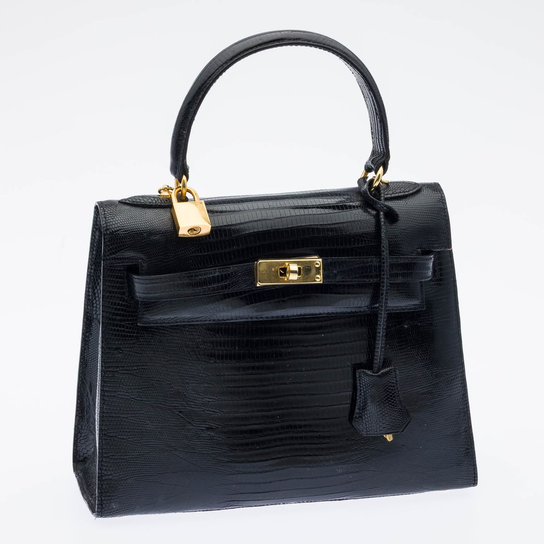 Lionhart Lizard Kelly Style Handbag: Description: Lionhart Lizard Kelly Style Handbag, with a structured trapezoidal shape, a single top handle, front toggle latch closure, internal zipped pocket, and thin removable strap; together with
