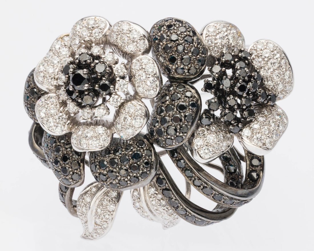 Black and White Diamond and 18K Flower Brooch: Description: Black and White Diamond and 18K Flower Brooch, featuring numerous pave set round cut diamonds (12 cts total) in 14K white gold with double stick-pin back, marked '18K, 750' on back.