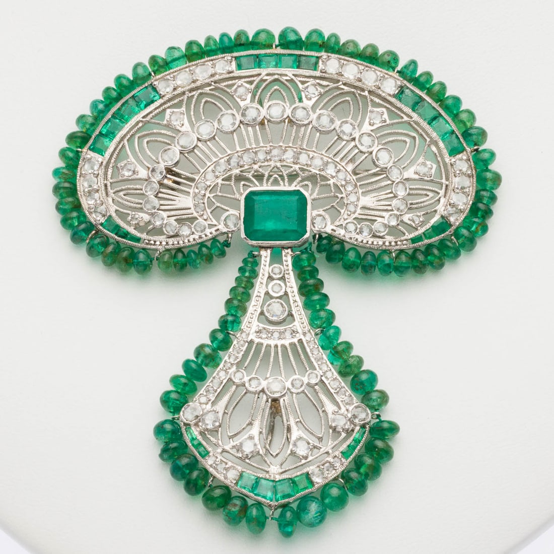 Emerald, Diamond and Platinum Pendant/Pin: Description: Emerald, Diamond and Platinum Pendant/Pin, featuring central rectangular cut emerald (approx. 3.5 cts) with other smaller square and baguette cut emeralds accented with various rose cut