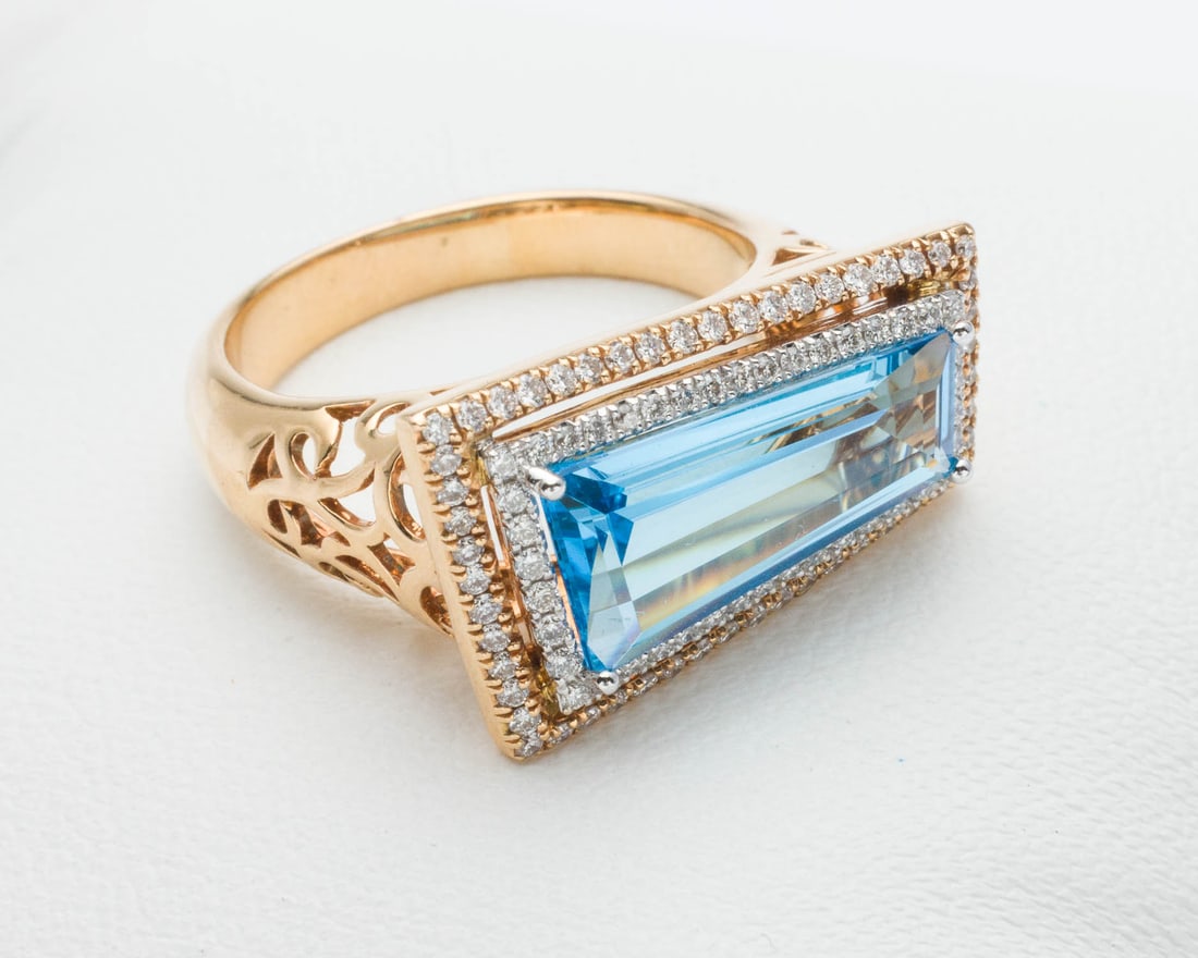 18K Gold, Blue Topaz and Diamond Ring, Size 7: Description: 18K Gold, Blue Topaz and Diamond Ring, Size 7, featuring a tapered baguette style blue topaz (approx. 15.6 mm x 7.5 mm) framed by two rows of near colorless round diamonds (approx. 0