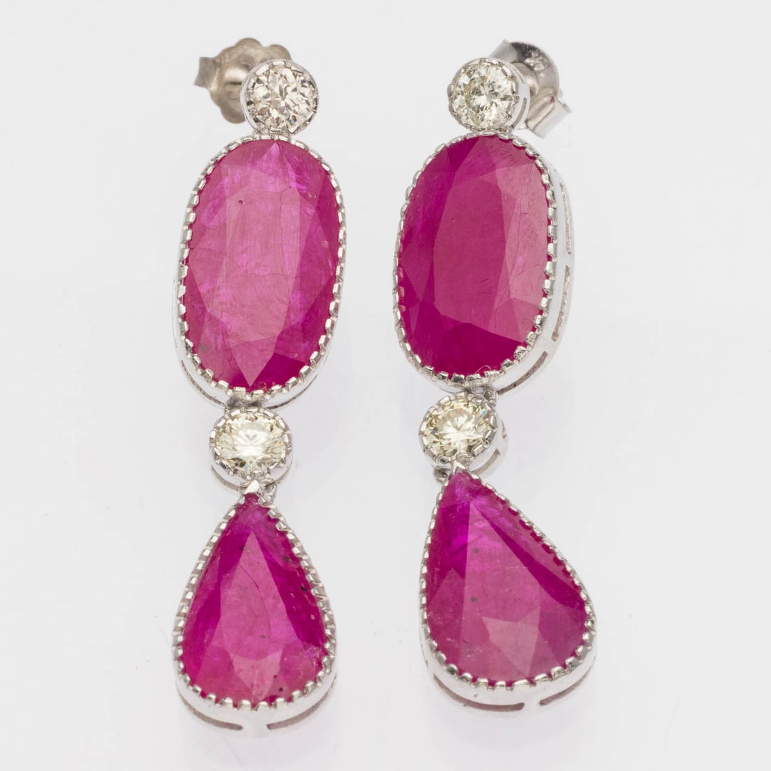 Ruby (15-17 cts) and Diamond Platinum Drop Earrings: Description: Ruby (15-17 cts) and Diamond Platinum Drop Earrings, each featuring a ova land pear cut ruby (approx. 15-17 cts total) and two round brilliant diamonds (approx. 1.00 cts total) beze