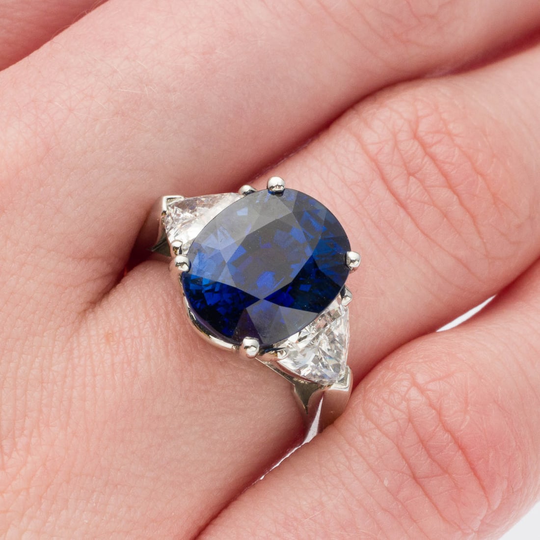 Sapphire (7.41 cts) & Diamond Plat Ring, AGL Cert: Description: Sapphire (7.41 cts) and Diamond Platinum Ring, Size 6.25, AGL Cert, featuring an oval mixed cut sapphire (7.41 cts, 12.32 x 9.86 x 7.26 mm, Madagascar, heated) flanked by two trillion