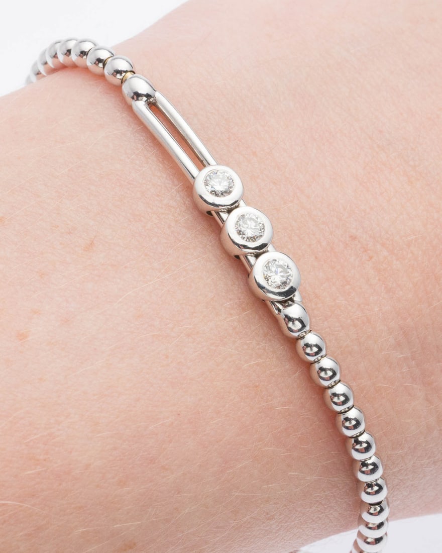 18K White Gold and Diamond Bracelet: Description: 18K White Gold and Diamond Bracelet, the expandable 18K white gold band featuring three sliding bezel set round diamonds (approx. 0.3 cts), marked '750' on back of band. 7.4 grams.
