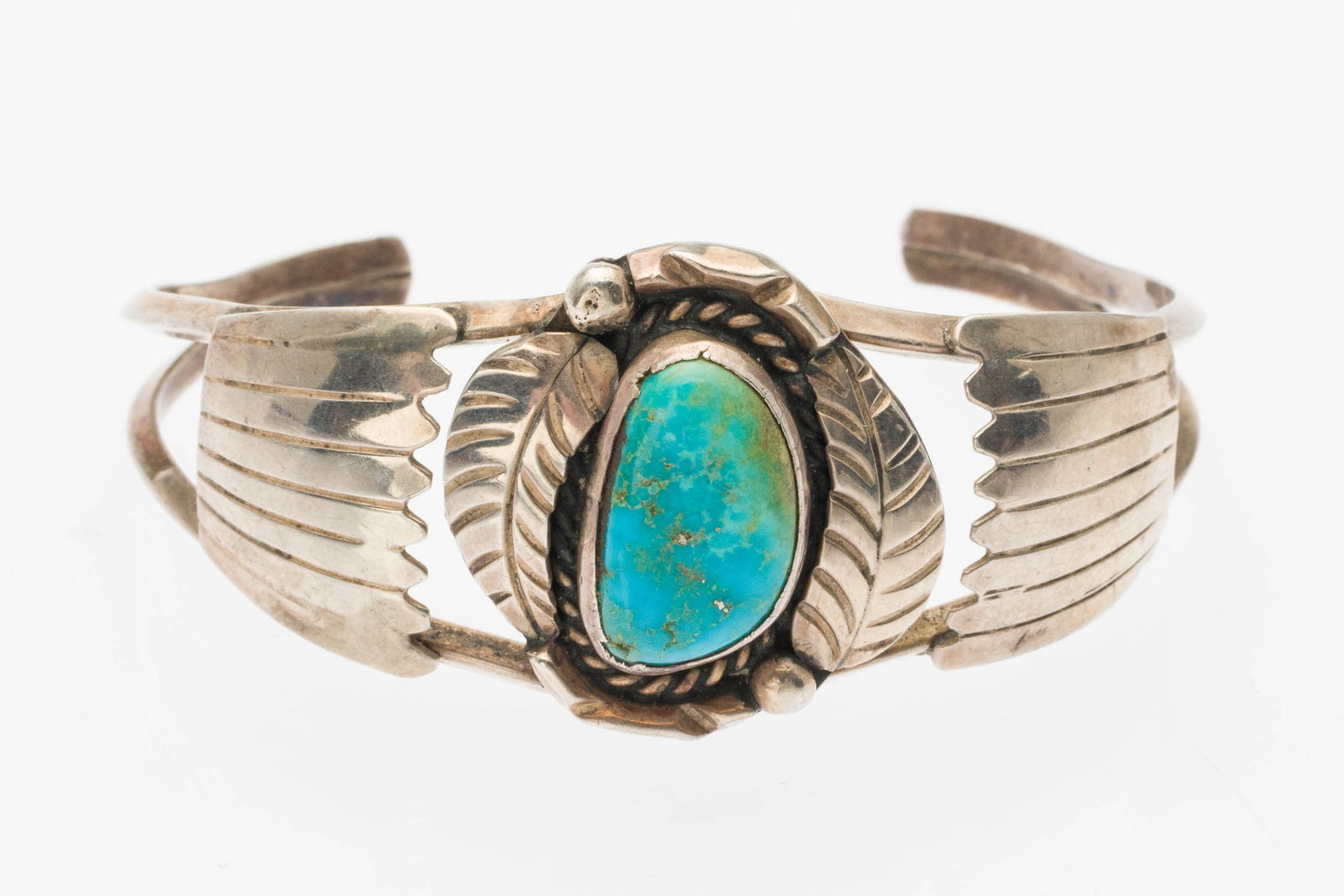 Native American Silver and Turquoise Cuff Bracelet: Description: Native American Silver and Turquoise Cuff Bracelet, featuring turquoise cabochon framed by feather motifs, stamped 'LP' on back. Measurements: Diameter: 2 3/8 in. x Width: of widest