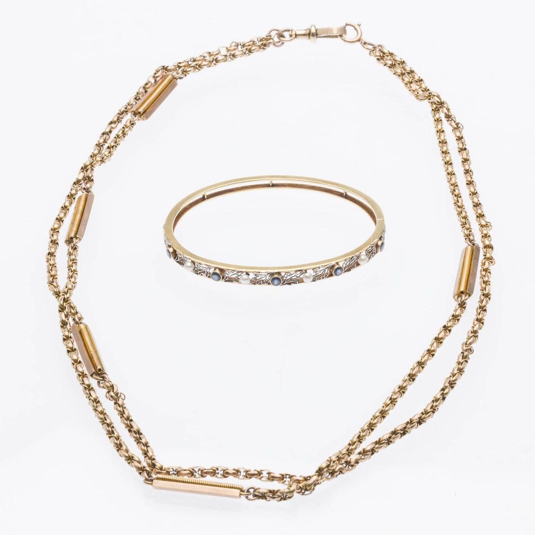 14K, Sapphire & Pearl Bracelet & Gold Filled Chain: Property of Sue McJames Description: 14K, Sapphire and Pearl Bracelet and Gold Filled Watch Chain, a pierced gold bangle bracelet featuring blue sapphires and seed pearls, with hinge and box clasp,