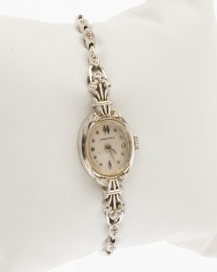 Longines 14K Gold Ladies Watch: Property from a Private Collection, Jacksonville, FL Description: Longines 14K Gold Ladies Watch, with white oval face in 14K white gold case, the bracelet featuring small round diamonds in each link