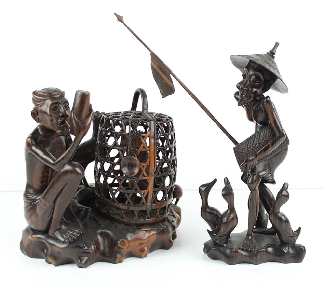 Balinese Carvings: MAN WITH CAGED BIRD; STANDING MAN WITH BIRDS, two hard wood carvings, inscribed Tantra Gallery Bali underneath, 8 ½” and 11 ½” tall, in good condition. (2)
