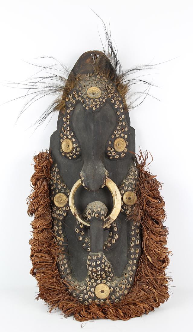 New Guinea Mask: Carved and patina wood mask with seashell and raffia beard, 21” x 10”, good aged condition.