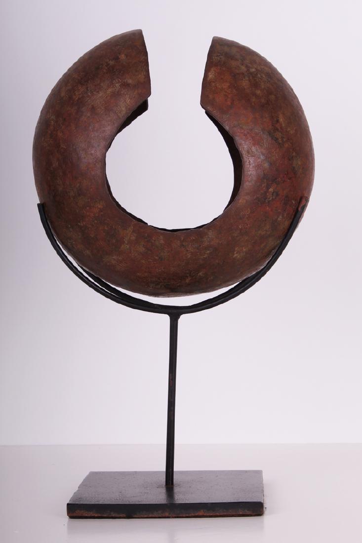 Object: African: Mbole currency anklet from the Congo, round metal object, 8 1/2" diameter, 5" deep, overall 15" tall with metal stand.