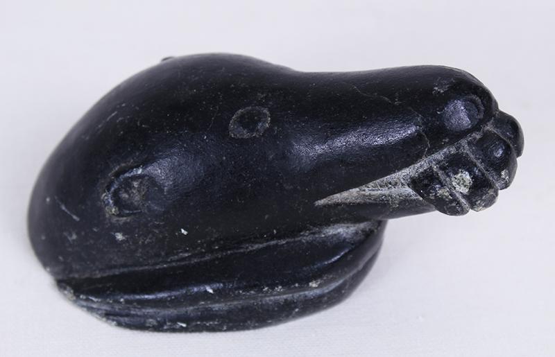 Inuit or Northwest Coast Artist (20 th Century): BEAR EATING HAND, 1953, carved black soapstone, possible signature hidden by affixed label, 2 ¾ x 5 x 2 ¾”. Provenance: Diana Zlotnick Collection, purchased from Canadian Craftâ��