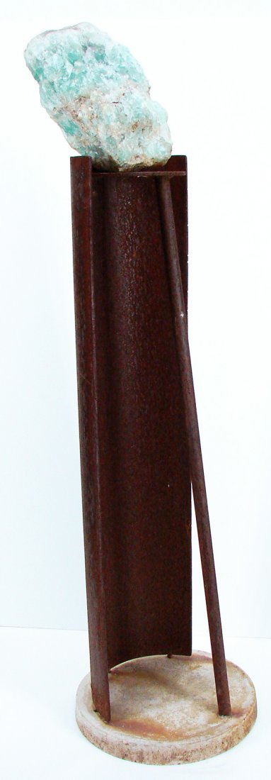 Robert Moore (b. 1936) Californian: QUARTZ STAND, welded steel with cement base and a resting green quartz rock on top, 58” tall, base 15 ½” diameter, rusted and weathered, otherwise in generally good condition.