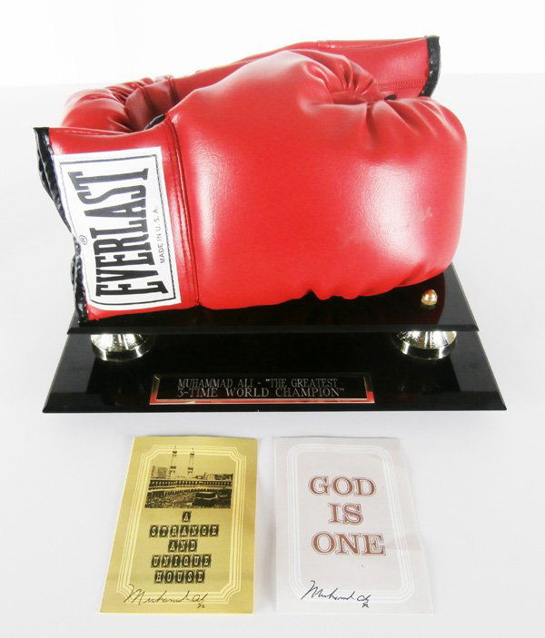 Muhammad Ali Sports Memorabilia: A pair of red Everlast boxing gloves, one hand signed (signature diminished), in custom Plexiglas box and stand, overall 9 x 13 x 10”, lid with speckled discoloration; Together with two Islamic pamp