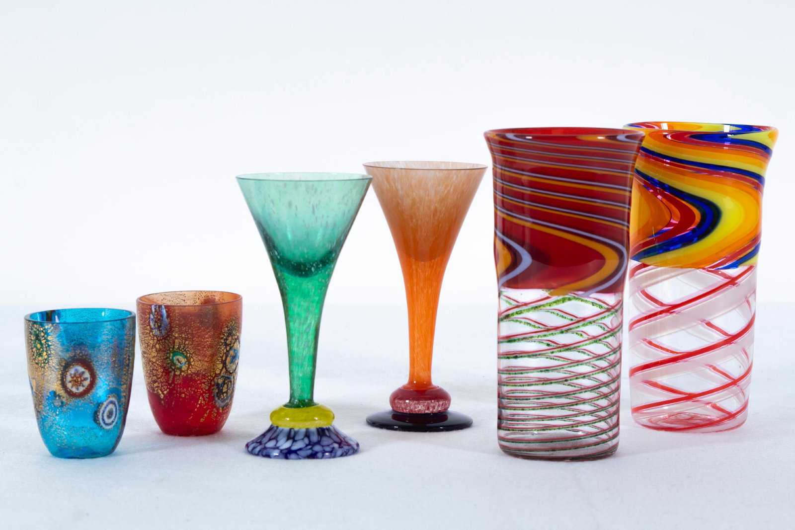 Art Glass & Fritz glass (six): A pair of small shot glasses with gold flecks, signatures or markings not found, each 2 ½” tall, 2” diameter; Together with two color wine glasses, both signed underneath, each 5 &f