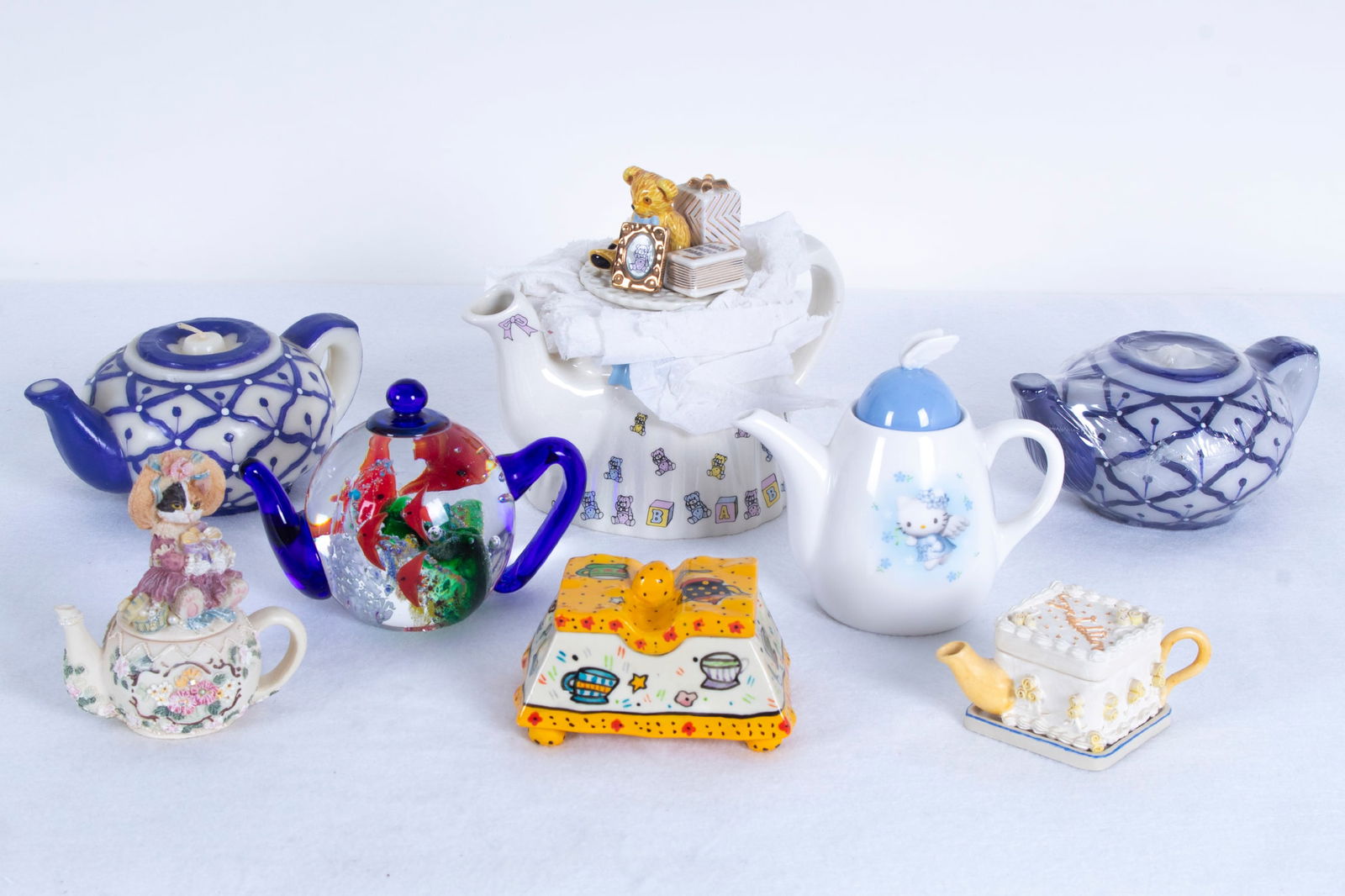 Teapot Collection (eight): Hello Kitty and Teddy Bear Cardew Collection two painted and glazed ceramic teapots each hallmarked underneath, 4 ½” tall & 5 ¾” tall; Together with a clear and colored glass