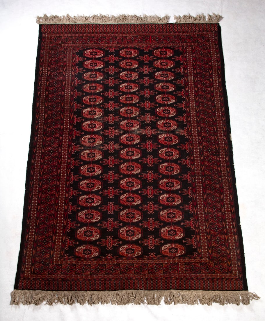 Bokkara Rug (circa 1960): Dyed and woven wool rug in reds, maroons and black with fringe on two sides, 74 x 48 ½”.