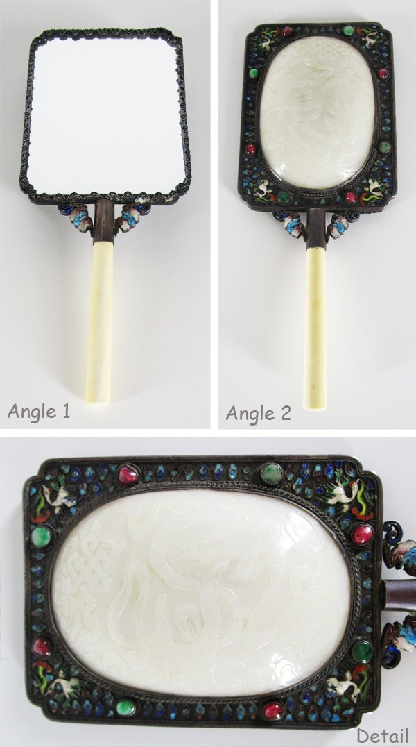 Decorative Arts: 19th Century Chinese Jade Hand-Mirror: Silver hand-mirror with elaborately carved white jade cabochon back, with cloisonné, filigree and inlaid stone, enameled bats flanking handle stem, 10 ¼” long, in good aged condition.