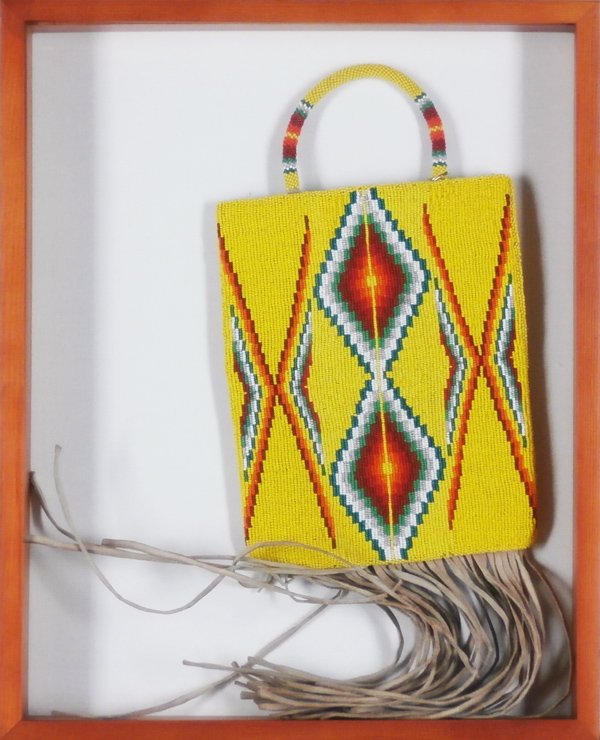 Native American Beaded pouch bag: One side extensively beaded tan hide with pattern, with beaded handle, one side lined inside, 24” overall length, in shadow box, lacking one strand of lower hide fringe, otherwise in apparently good