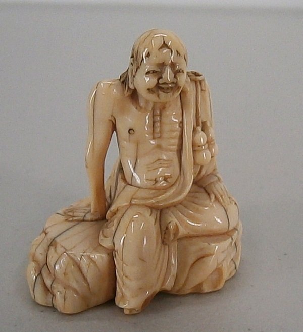 Netsuke: SEATED SAGE, 2 ¼” tall, carved with large cord holes, probably Edo period, in apparently good aged condition.