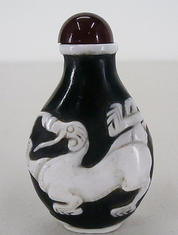 Snuff Bottle: Chinese black with white glass over-lay and carnelian color cap, dragon design, 2 7/8” tall, in apparently generally good aged condition.