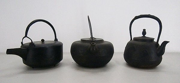 Cast Iron Teapots (three): Three Japanese cast-iron teapots with removable lids, all with handles, one with movable handle and inscription underneath lid, average 6 ½” diameter, all in apparently generally good aged conditio