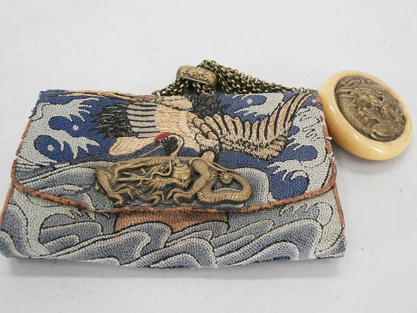 Tobako-ire: Antique tobacco pouch of embroidered cloth over tooled leather, with brass dragon clasp, with ivorine and repousse metal kagamibuta manju netsuke attached with ornamental chain-work, 5 ½ x 4”, in a