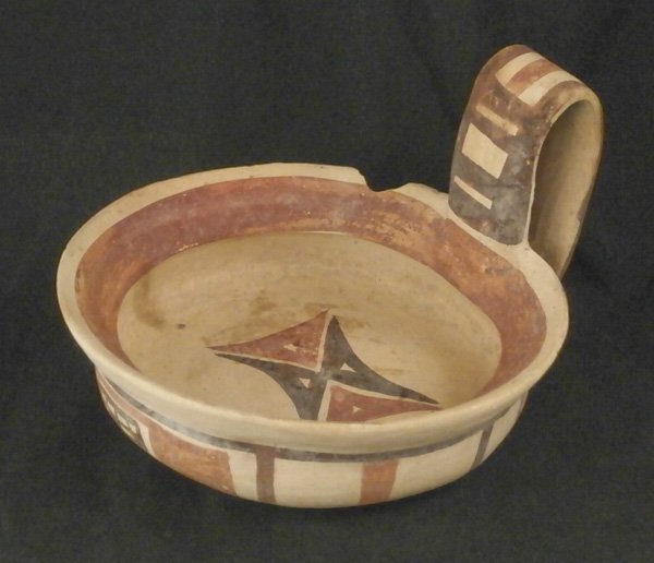 Decorative Arts: Daunian Pottery: Painted earthenware dish with red and brown geometric patterns, with extended handle, 4 x 5 ¾ x 6 ¼”, in good aged condition.