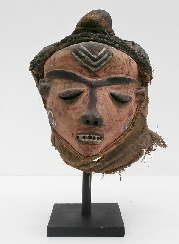 African Mask: Pende mask, elaborately carved and painted wood with neck and bun cloths and woven fiber braids, early to mid-20th century with unfinished interior, 13” from top to bottom neck cloth, 17 ” top to 