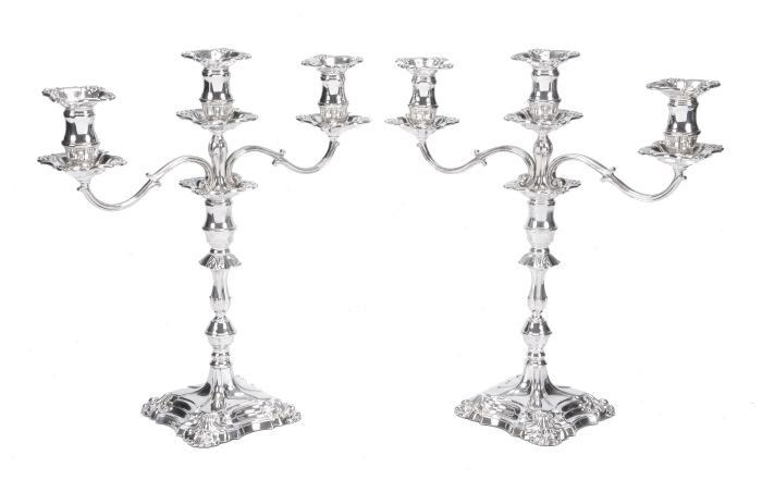 A pair of silver twin branch three light candelabr: A pair of silver twin branch three light candelabra by Roberts & Belk Ltd, Sheffield 1975, shaped square with shell angles, with detachable sconces to the reel capitals with drip pans, scroll