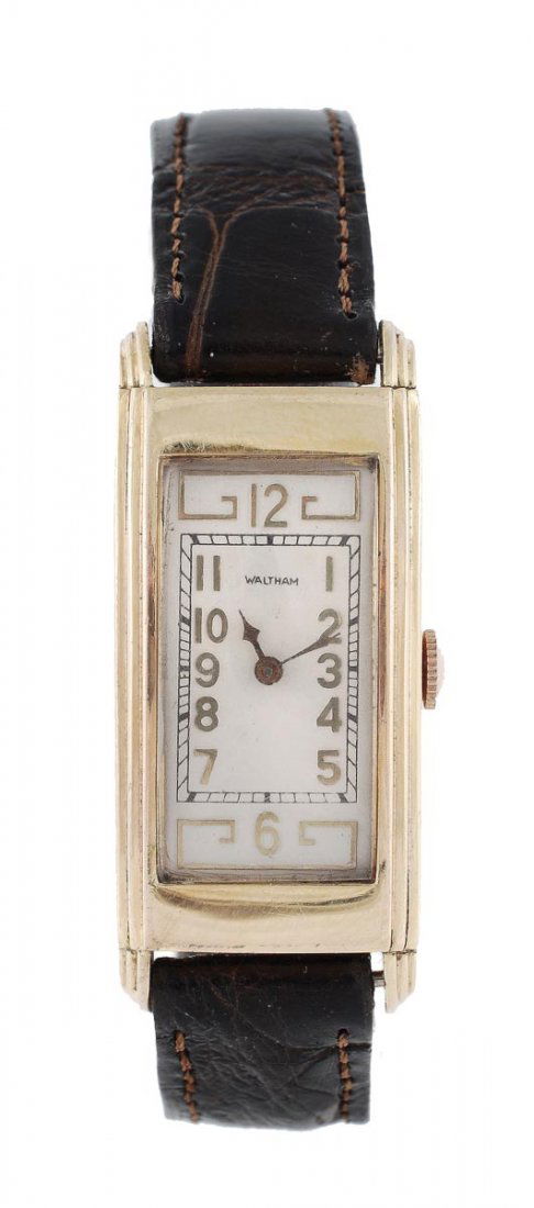 Waltham, a 1930s gold plated wristwatch, the two p: Waltham, a 1930s gold plated wristwatch, the two piece curved rectangular case with stepped side, the cream dial with applied Arabic numerals and arrow hands, the 15 jewel Waltham movement no