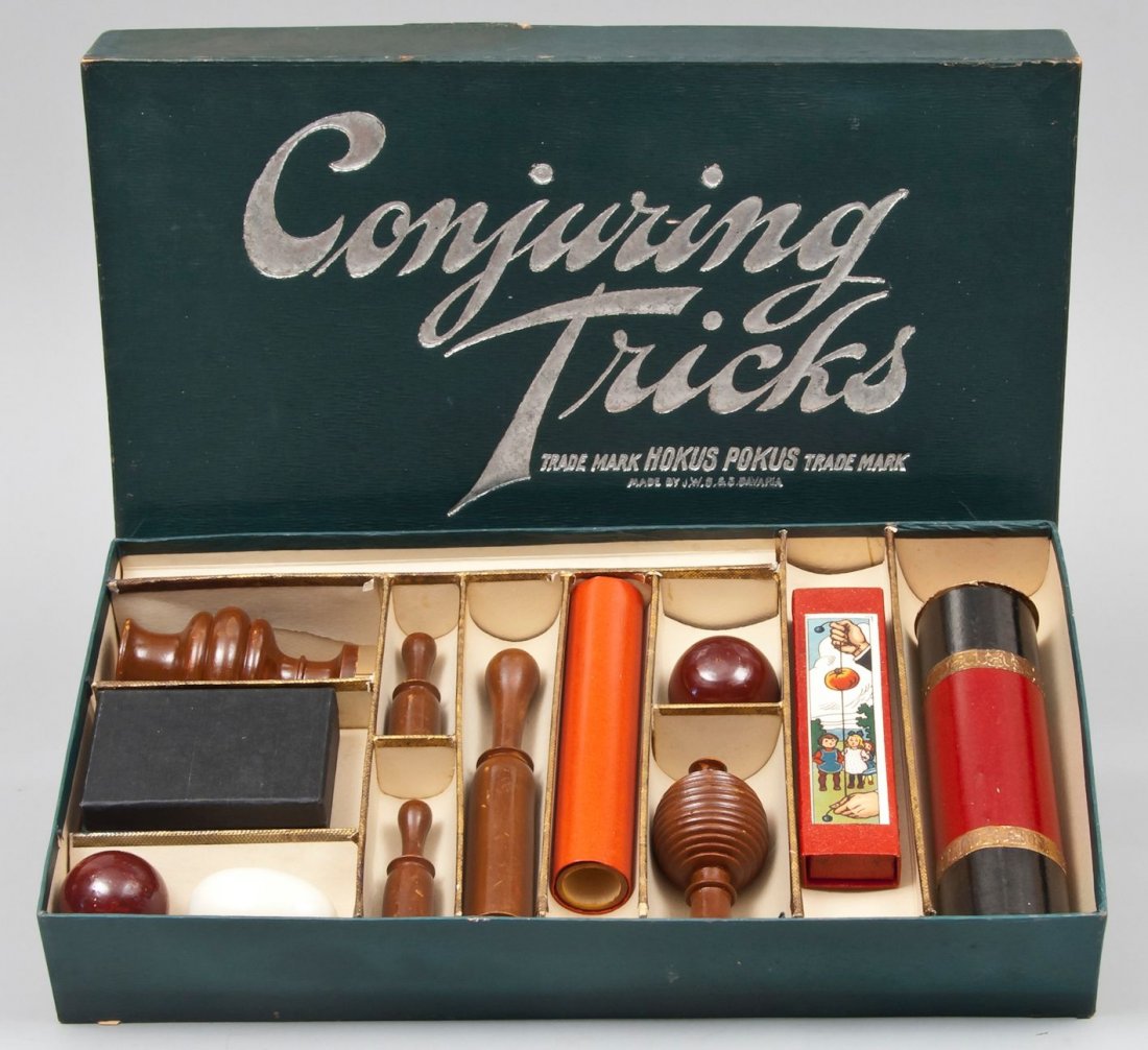 Conjuring Tricks,: card box containing 11 tricks and wand, 9 of the pieces in original wrapping, with three different instruction booklets, the lid printed in silver, split along one edge, 234mm. by 435mm., J.W.S[pear] 