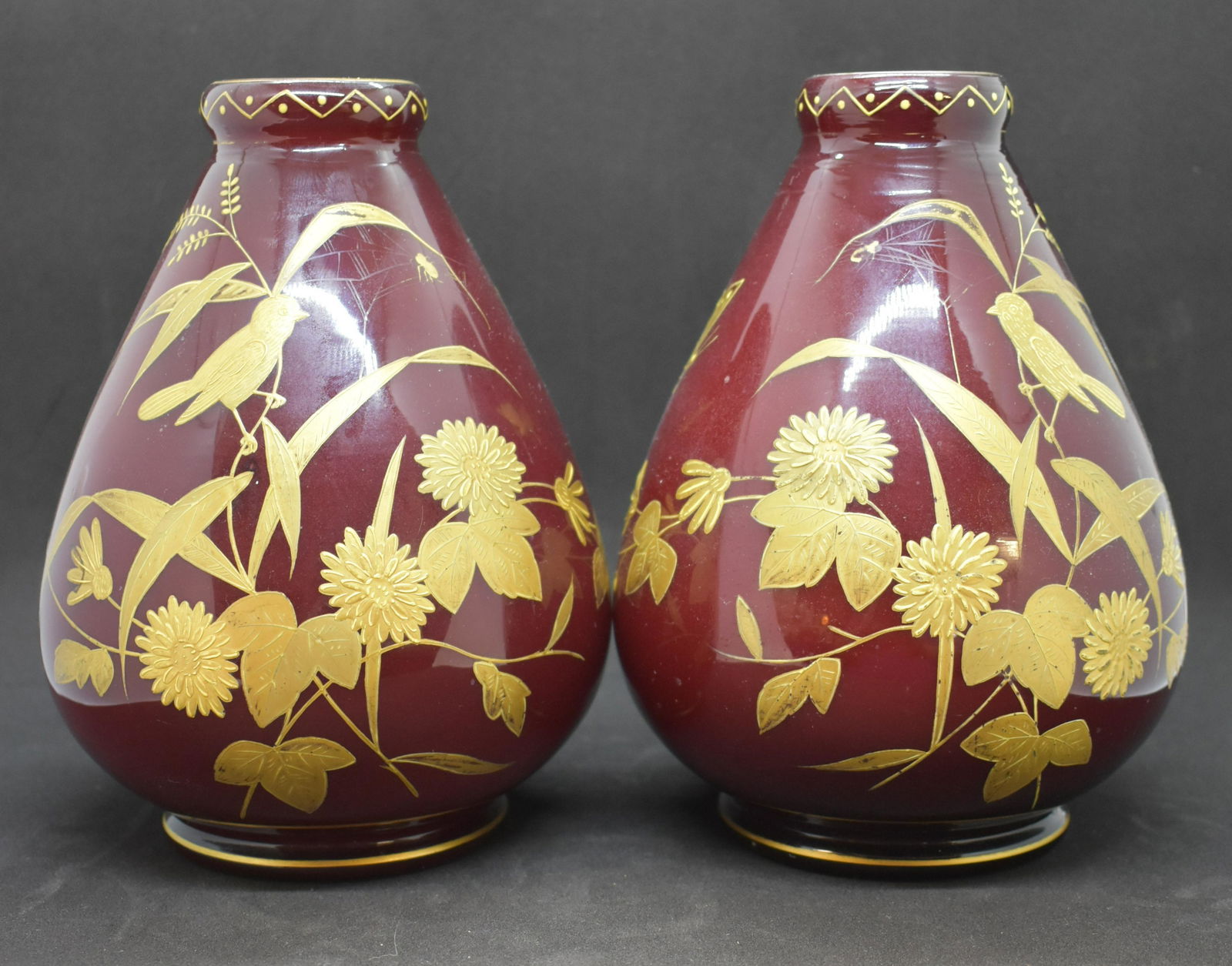 Thomas Webb Ox Blood Bird & Flower Vases: Cased glass, ox blood red over white with gilt decor. Pair of vases measures approx. 6.75" tall. See Photos for Details. Shipping Available.