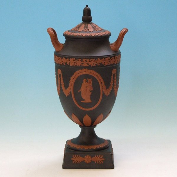 Wedgwood modern lidded twin handled black basalt a: Wedgwood modern lidded twin handled black basalt and terracotta vase decorated with classical figures playing harps within cartouches and floral swags with turned foot and square base, impressed marks