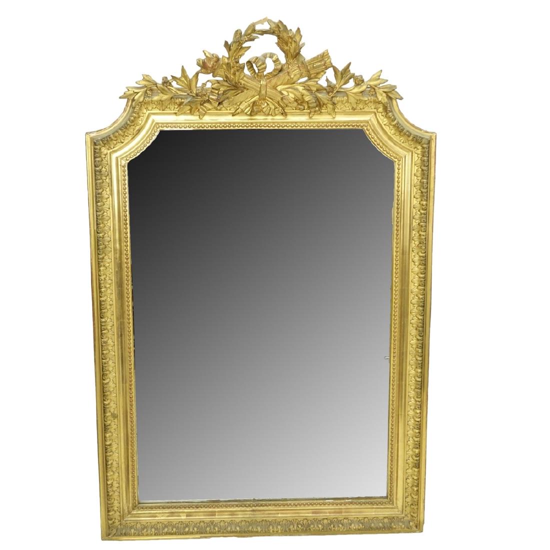 Antique French Giltwood Mirror: Antique French Louis XVI Style Giltwood Carved Mirror. Decorated with ribbons, leaves , and crossed torch in quiver. Measures 50-5/8" H x 32-1/2" W. Condition: Losses to top decoration, scratches and 