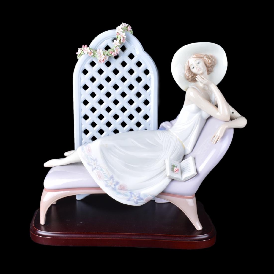 Lladro Figurine: Lladro porcelain figurine of a lady reclining on a chaise lounge with trellis backdrop with base. Signed. Measures 12-1/2" H x 14" W. Condition: On flower petal missing on top of trellis or in good co