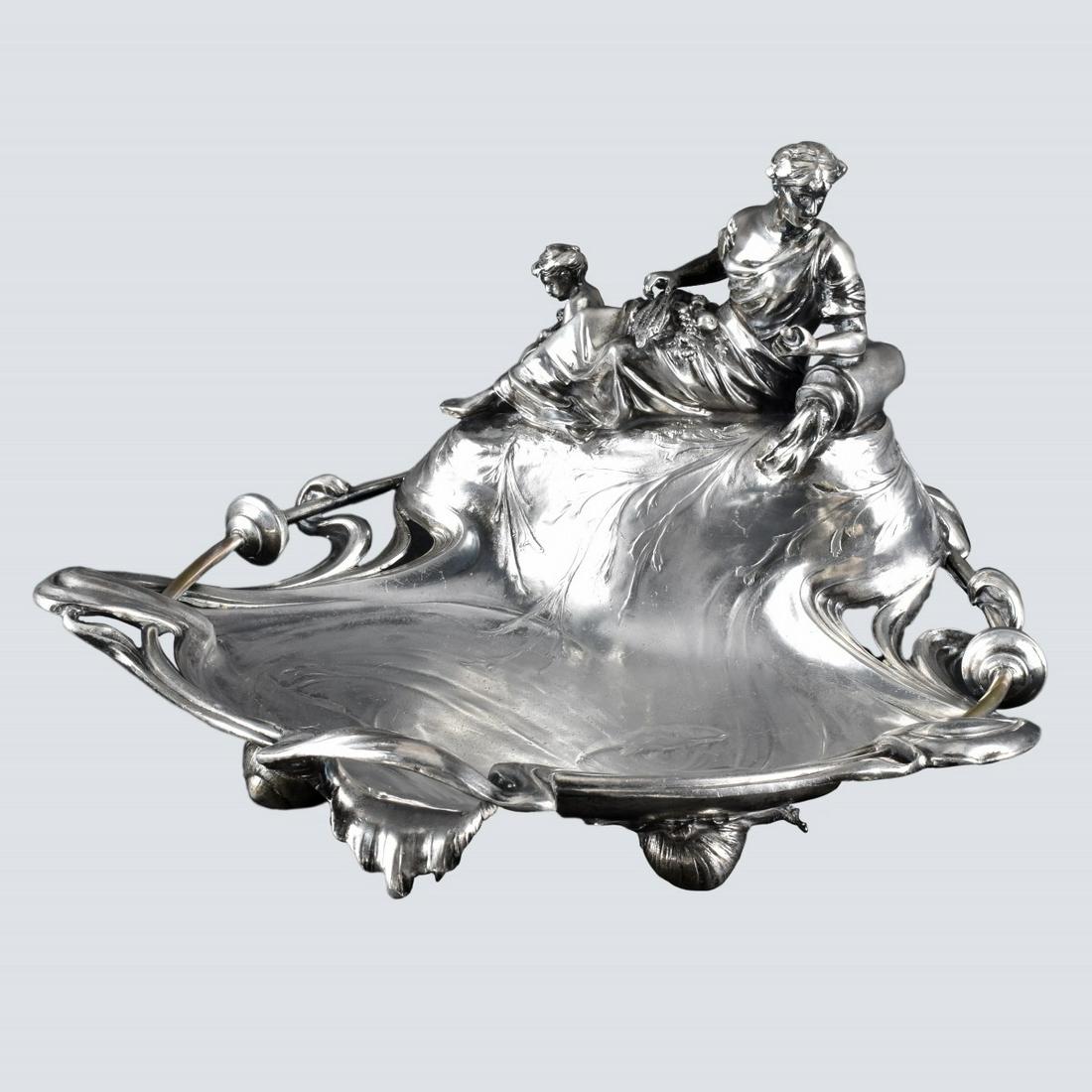 Art Nouveau Silverplate Figural Centerpiece: Art Nouveau Silverplate Figural Centerpiece. Lady with fruit in her lap, sitting on hill with boy with fish above a pond with fish swimming in it. Signed to bottom foundry mark possibly WMF. Measures 