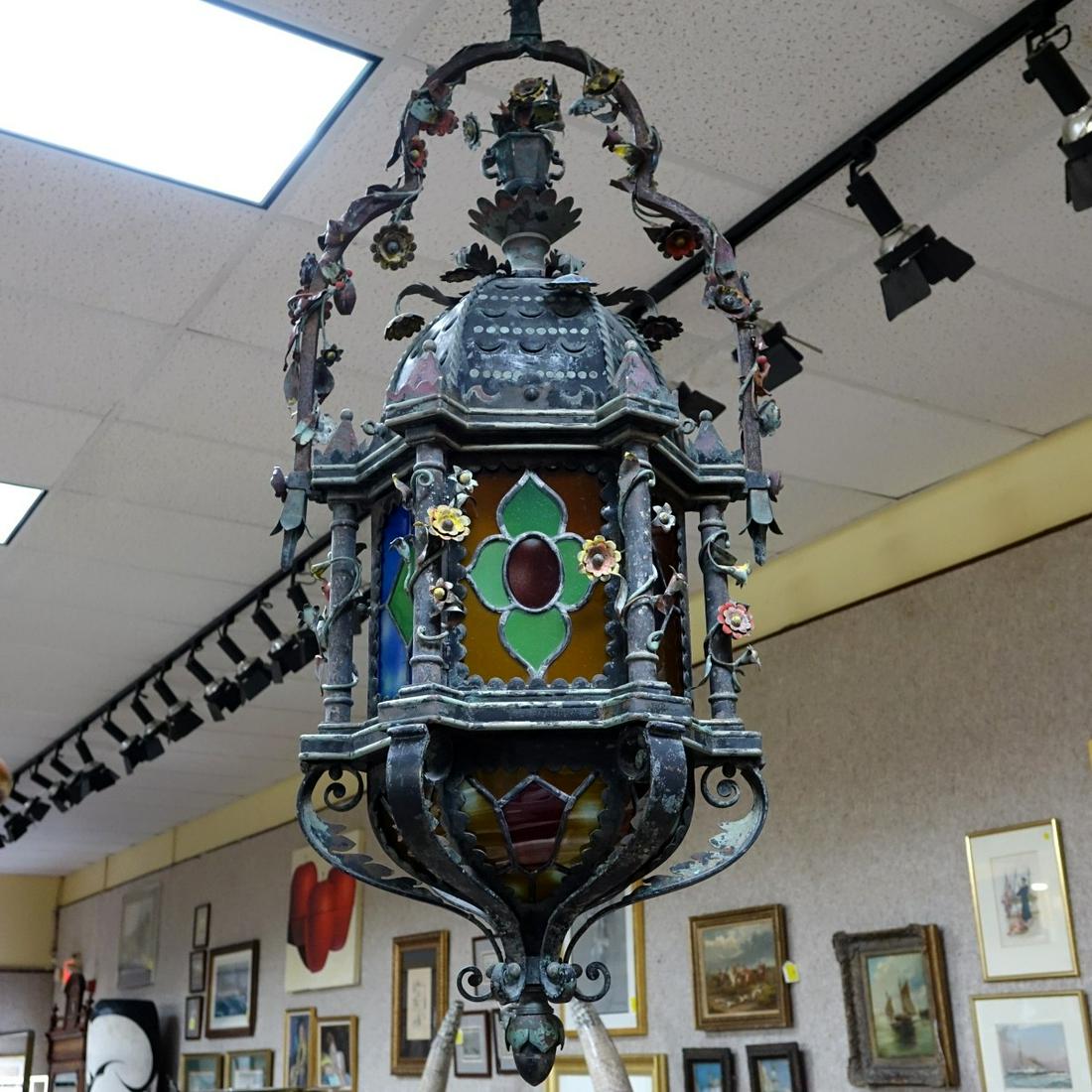 Early 20C Wrought Iron lantern: Early 20th Century Moorish Style Wrought Iron Stain Glass Ornate Hanging Lantern, boughs of flowers surrounding the basket style handle at the top down the sides . Measures approx. 51" H x 20" W Condi