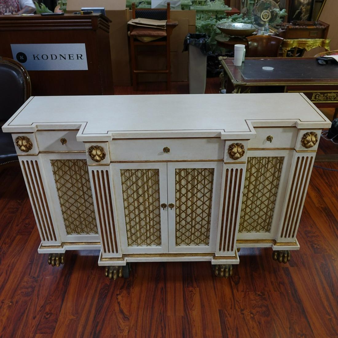 Jansen Style Neoclassical Sideboard: Style of Jansen Neoclassical Style White and Gilt Painted Sideboard. Two large center doors beneath three sliding drawers with lined interior, lion heads relief and stand on paw feet, and brass pulls.