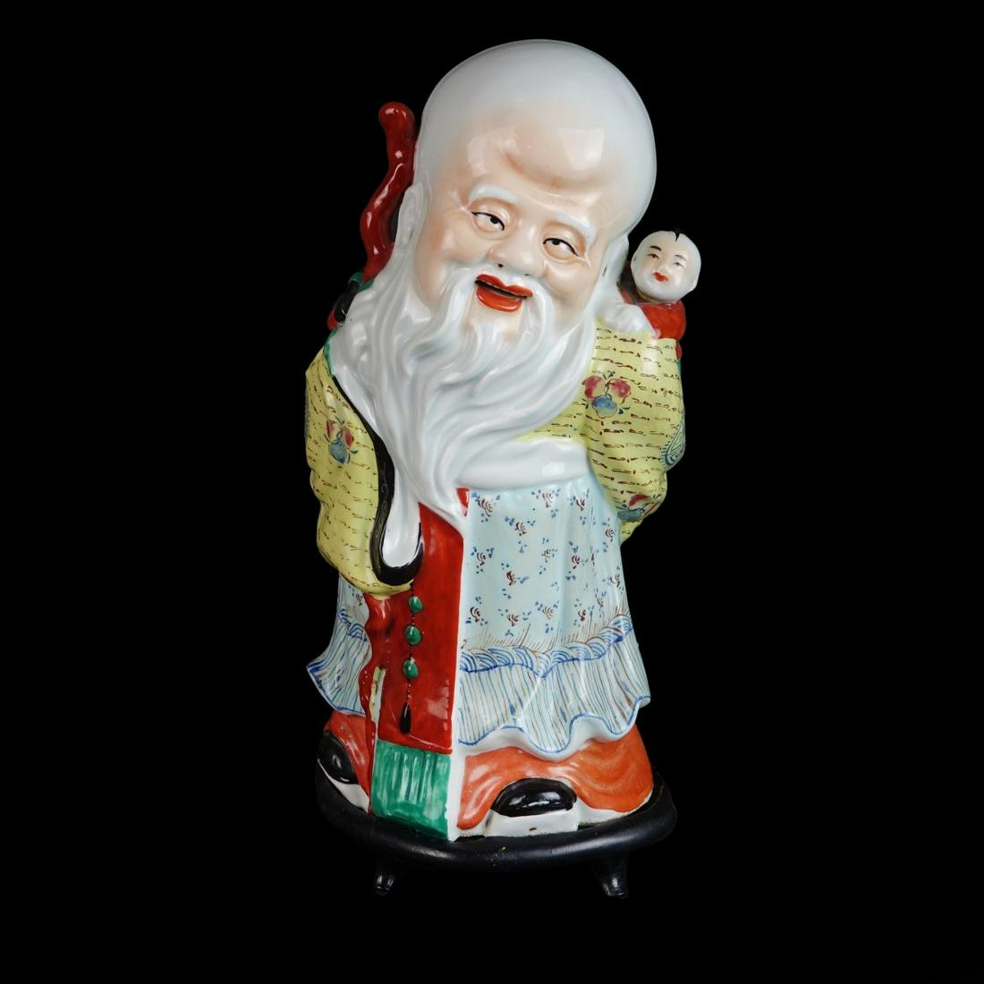 Large Vintage Chinese Porcelain Figurine: Large Vintage Chinese Porcelain Shou Lao Immortal and Child Figurine Presented on Wooden Base. Stamp mark on the bottom side. Figurine measures 14" H x 6" W. Overall measures 15" H. Condition: Good co