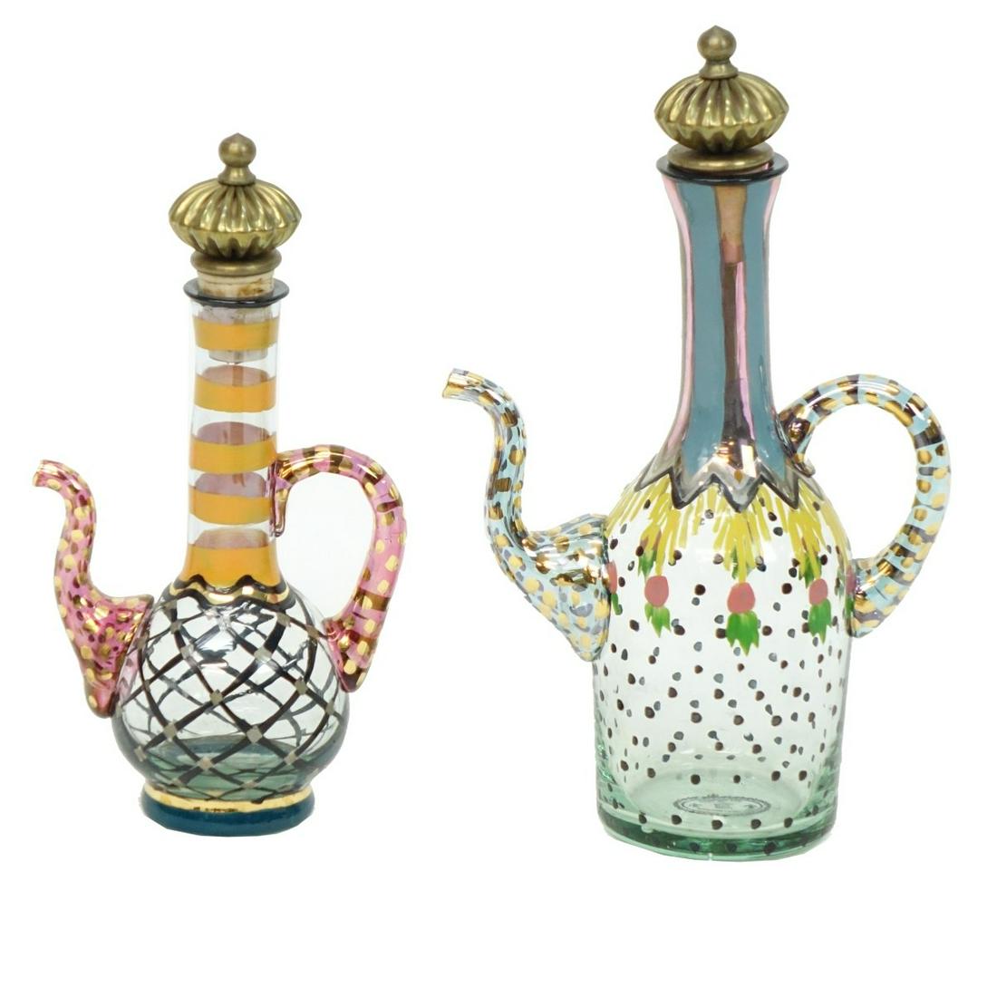Mackenzie Childs Glass Cruets: Mackenzie Childs Handpainted Glass Oil and Vinegar Cruets with Stoppers. Each bearing original labels. Tallest measures 8", other measures 7". Condition: Good condition. Estimate: $50.00 - $150.00 Dom