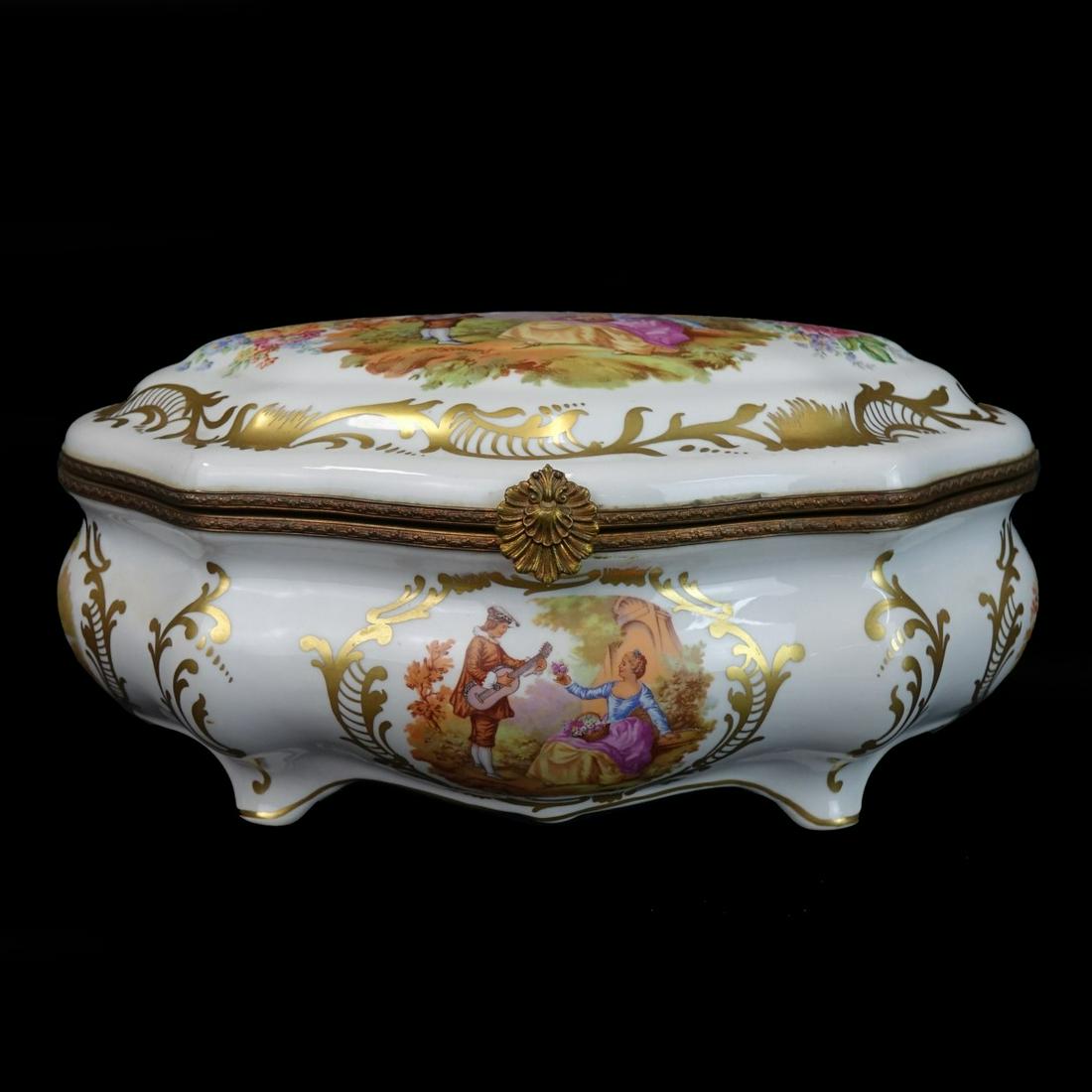Dresser Box: Large Sevres Porcelain Dresser Box. Signed. Bronze mounted and courting scenes throughout the surface. Measures 6-1/4" x 13". Condition: Good condition. Estimate: $100.00 - $300.00 Domestic Shipping: 