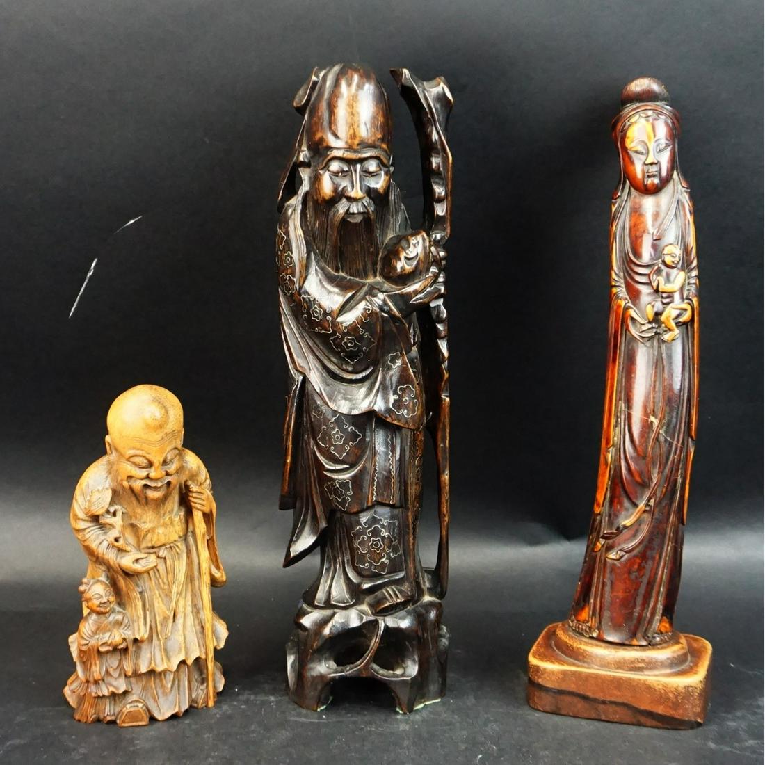 Chinese Figurines: Antique Chinese Tea Stained Bone Carved Guanyin Figurine together with Two Chinese Wood Carved Buddha Figurines. Bone figurine measures 14-1/8" x 4" x 3". Tallest wood carved Buddha measures 14-3/8" x