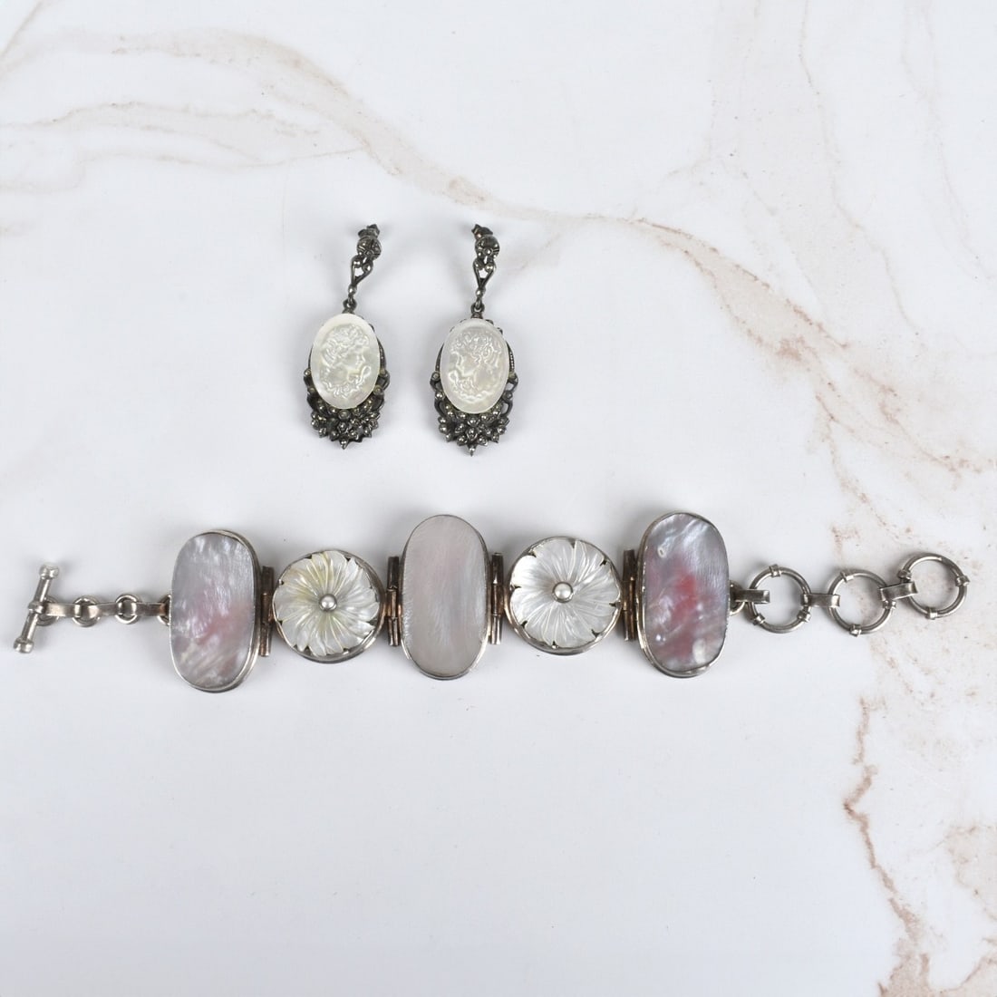 MOP and Sterling Jewelry: Vintage Carved Mother of Pearl and Sterling Silver Five Panel Bracelet together with Carved Mother of Pearl, Marcasite and Sterling Silver Cameo Pendant Earrings. Bracelet stamped 925. Bracelet measur