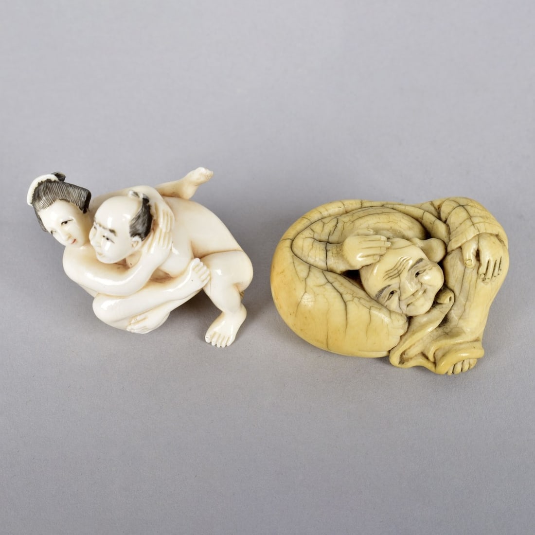 Two Antique Japanese Netsuke Figurines: Grouping of Two Antique Japanese Miniature Netsuke Figurines. Includes a polychrome erotic group together with a Buddha. Erotic group measures 1-5/8" x 1-1/2". Buddha measures 1" x 2". We Will Not Shi