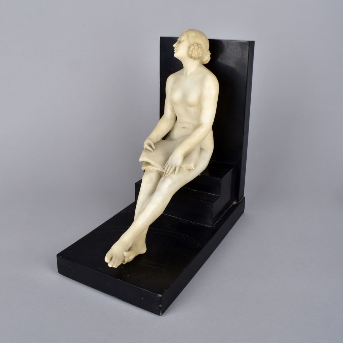 Alabaster Nude Reading: Alabaster Nude Reading, sitting on a black marble step with braided hair coiled around her ear. Signed to black marble G Goumlogi? Measures 11-1/2"H x 5-3/4"W x 11"L. Condition: Good Condition, loose